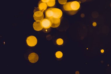 Siyah arkaplanda koyu soyut altın bokeh parıltısı