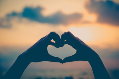 Eller kalp şeklinde aşk yapar. Gün batımında siluetle.