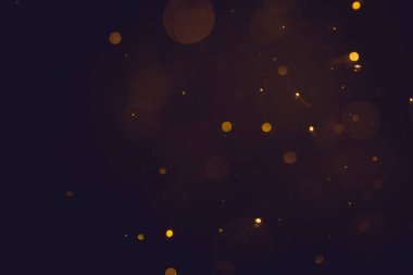 Siyah arkaplanda koyu soyut altın bokeh parıltısı