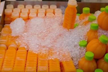 Soğuk portakal suyu şişede, buzlu arka planda yenilenmek için içmeye hazır.