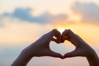 Eller kalp şeklinde aşk yapar. Gün batımında siluetle.