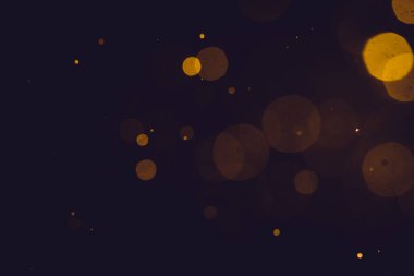 Siyah arkaplanda koyu soyut altın bokeh parıltısı