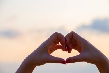 Eller kalp şeklinde aşk yapar. Gün batımında siluetle.