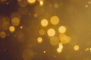 Siyah arkaplanda koyu soyut altın bokeh parıltısı