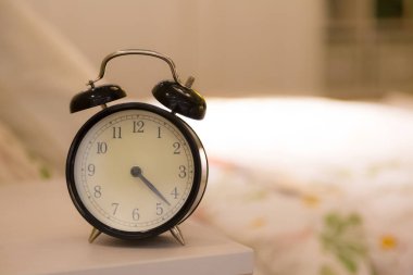 Yatağın başucunda, bulanık yatak arkaplanı olan çalar saat.