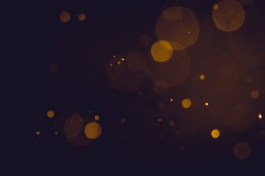 Siyah arkaplanda koyu soyut altın bokeh parıltısı