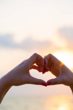 Eller kalp şeklinde aşk yapar. Gün batımında siluetle.