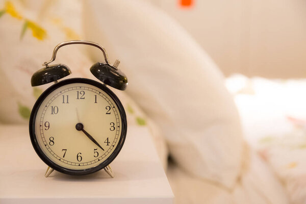 Будильник, на кровати с размытым фоном кровати