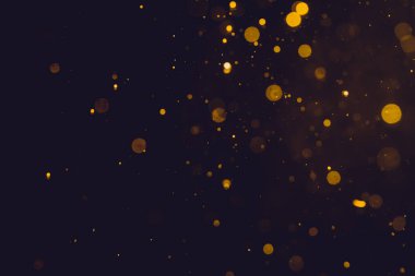 Siyah arkaplanda koyu soyut altın bokeh parıltısı