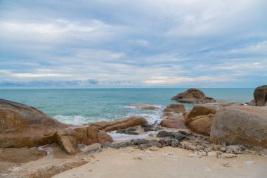 Kumsalda kum ve mavi gökyüzü zeminli deniz ve kaya taşları