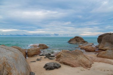 Kumsalda kum ve mavi gökyüzü zeminli deniz ve kaya taşları