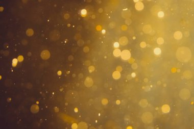 Siyah arkaplanda koyu soyut altın bokeh parıltısı