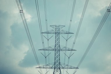Yüksek voltaj direği kablosu ve bulutlu mavi gökyüzü.
