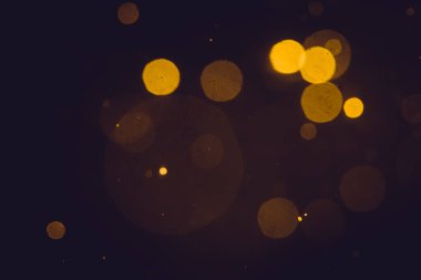 Siyah arkaplanda koyu soyut altın bokeh parıltısı