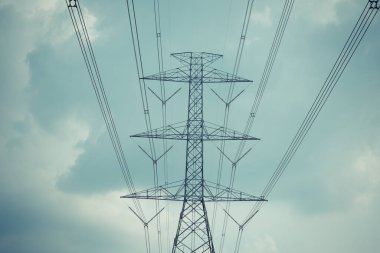 Yüksek voltaj direği kablosu ve bulutlu mavi gökyüzü.