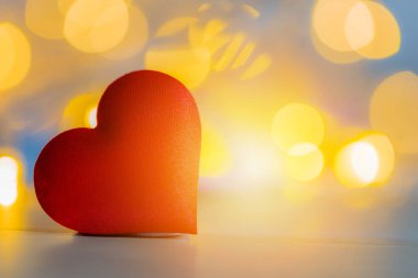 Ahşap masada yumuşak bokeh arkaplanlı kırmızı kalp şekli