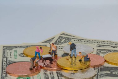 Miniture people with crypto gold silver bronzen bitcoin with dollar banknotes background