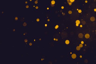 Siyah arkaplanda koyu soyut altın bokeh parıltısı