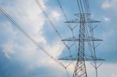 Yüksek voltaj direği kablosu ve bulutlu mavi gökyüzü.