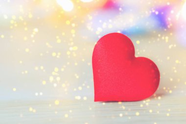 Ahşap masada yumuşak bokeh arkaplanlı kırmızı kalp şekli