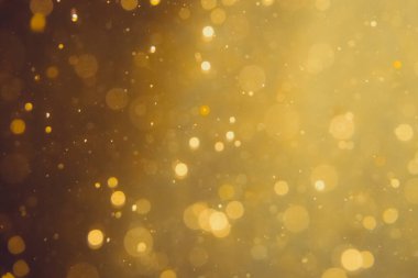 Siyah arkaplanda koyu soyut altın bokeh parıltısı