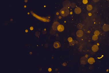Siyah arkaplanda koyu soyut altın bokeh parıltısı