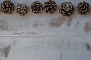 Beyaz, eski ahşap arka planda kurumuş çam topları.