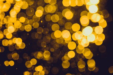 Soyut altın koyu arkaplanda odaklanmış ışık bokeh 'i