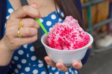 Kırmızı şuruplu buzlu tatlılar ve doğal arka planda el ele tutuşan kadınlarda tatlı süt.