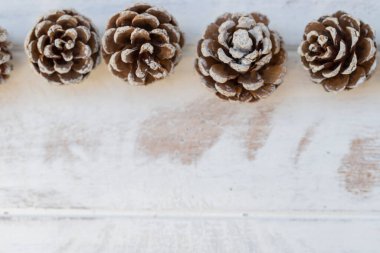 Beyaz, eski ahşap arka planda kurumuş çam topları.