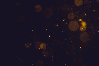 Siyah arkaplanda koyu soyut altın bokeh parıltısı
