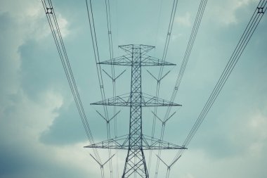 Yüksek voltaj direği kablosu ve bulutlu mavi gökyüzü.