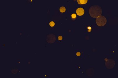 Siyah arkaplanda koyu soyut altın bokeh parıltısı