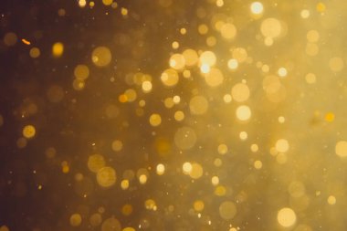 Siyah arkaplanda koyu soyut altın bokeh parıltısı