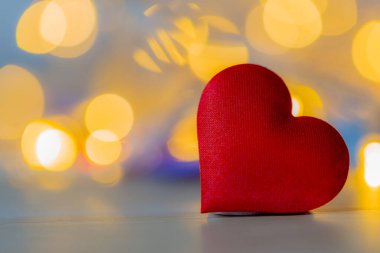 Ahşap masada yumuşak bokeh arkaplanlı kırmızı kalp şekli