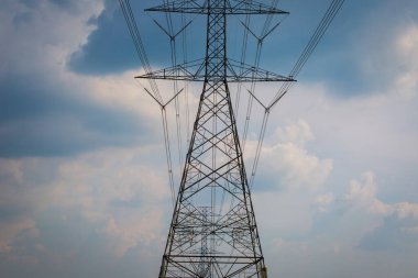 Yüksek voltaj direği kablosu ve bulutlu mavi gökyüzü.
