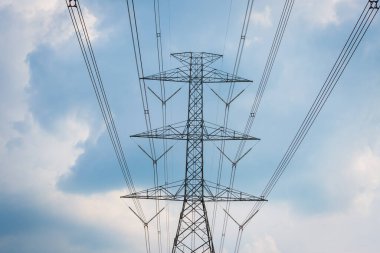 Yüksek voltaj direği kablosu ve bulutlu mavi gökyüzü.