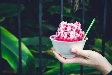 Kırmızı şuruplu buzlu tatlılar ve doğal arka planda el ele tutuşan kadınlarda tatlı süt.