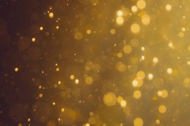 Siyah arkaplanda koyu soyut altın bokeh parıltısı