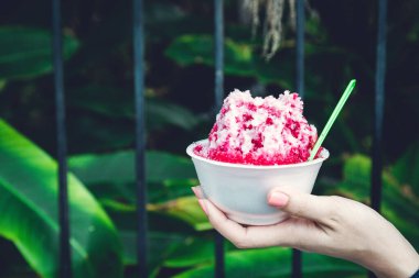 Kırmızı şuruplu buzlu tatlılar ve doğal arka planda el ele tutuşan kadınlarda tatlı süt.