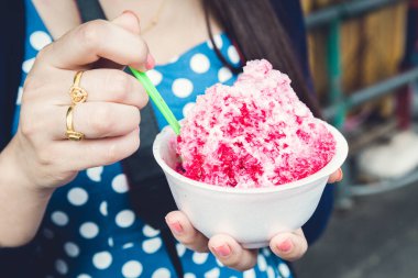 Kırmızı şuruplu buzlu tatlılar ve doğal arka planda el ele tutuşan kadınlarda tatlı süt.