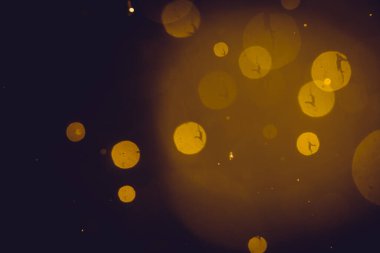 Siyah arkaplanda koyu soyut altın bokeh parıltısı