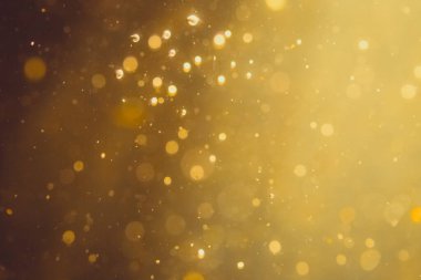 Siyah arkaplanda koyu soyut altın bokeh parıltısı