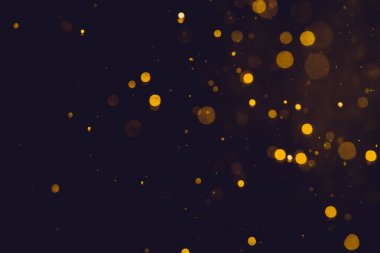 Siyah arkaplanda koyu soyut altın bokeh parıltısı