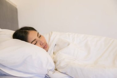 Yatak odasında beyaz yastıkta uyuyan güzel bir kadın.