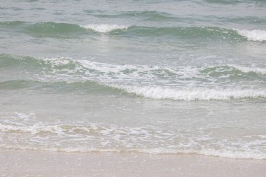 Mavi deniz, kumsal dalgalarıyla birlikte ışığı yansıtıyor.