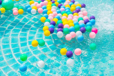 Yüzme havuzunda turkuaz ışığı yansıtan renkli toplar.