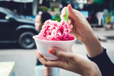 Kırmızı şuruplu buzlu tatlılar ve doğal arka planda el ele tutuşan kadınlarda tatlı süt.