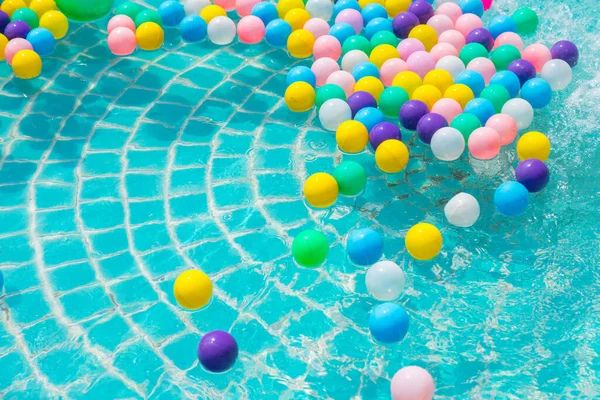 Yüzme havuzunda turkuaz ışığı yansıtan renkli toplar.