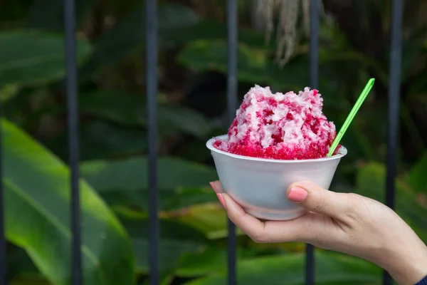 Kırmızı şuruplu buzlu tatlılar ve doğal arka planda el ele tutuşan kadınlarda tatlı süt.